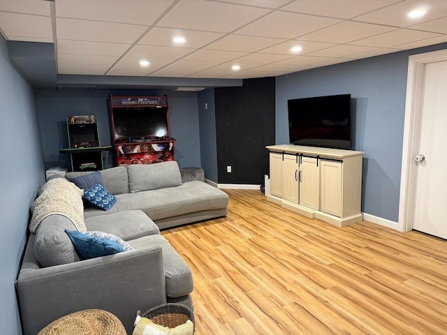 living room featuring baseboards, light wood-type flooring, a paneled ceiling, and recessed lighting