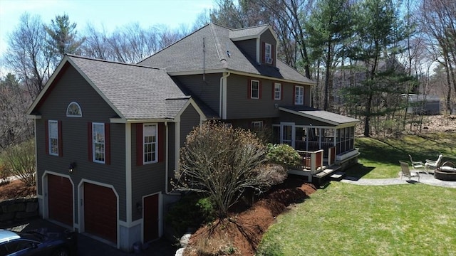 view of home's exterior featuring a lawn, a sunroom, a garage, and roof with shingles