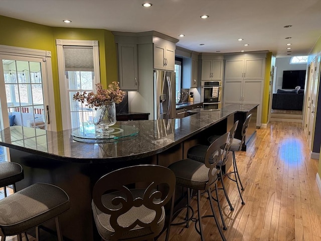 kitchen with recessed lighting, gray cabinetry, a kitchen bar, and stainless steel appliances