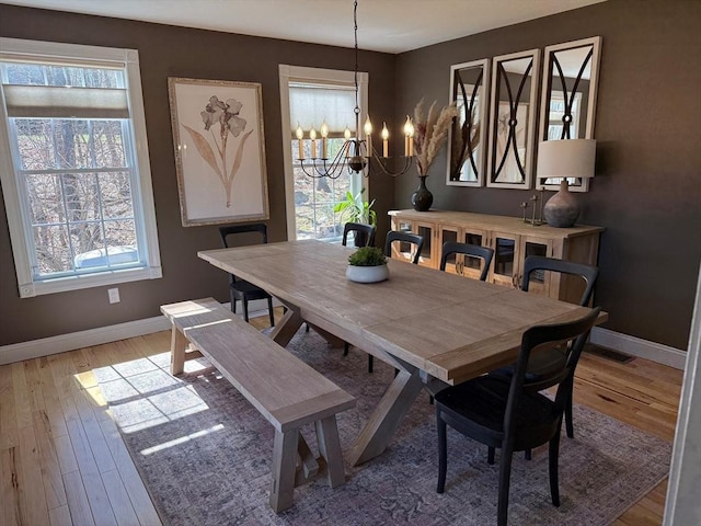 dining space featuring baseboards, a wealth of natural light, an inviting chandelier, and wood finished floors