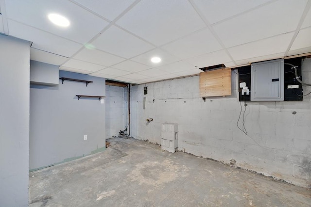 basement featuring a paneled ceiling and electric panel