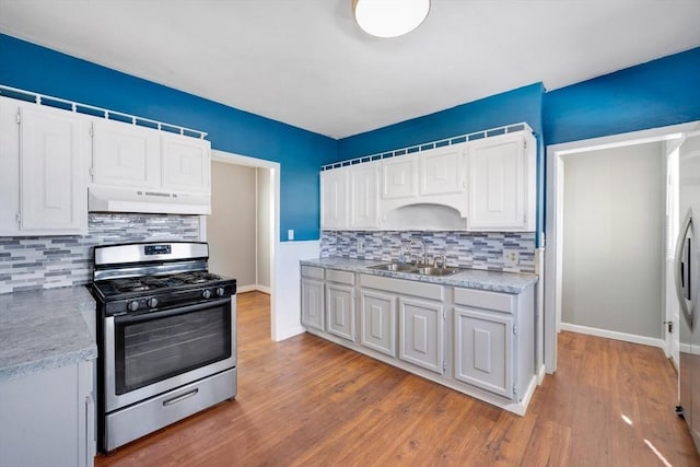 kitchen with sink, white cabinetry, backsplash, stainless steel gas range oven, and wood-type flooring