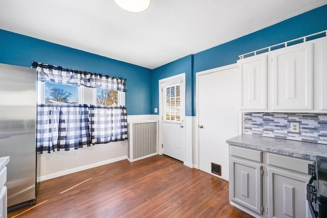 kitchen featuring stainless steel fridge, white cabinetry, backsplash, stove, and dark hardwood / wood-style floors