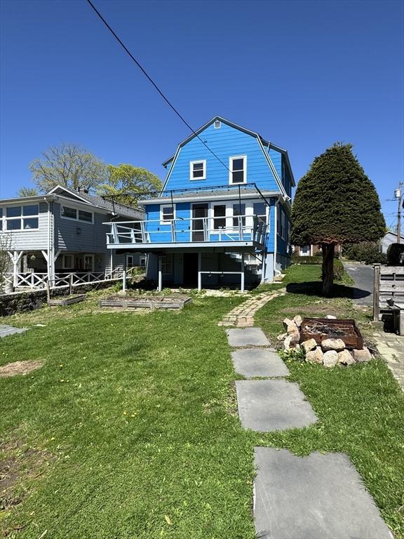 rear view of house with a lawn, a deck, and a gambrel roof