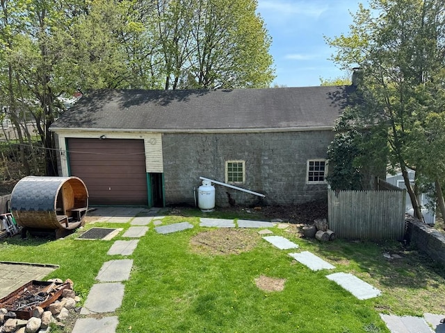 exterior space featuring a garage, fence, a lawn, and driveway