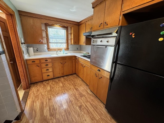 kitchen with freestanding refrigerator, open shelves, oven, light countertops, and under cabinet range hood