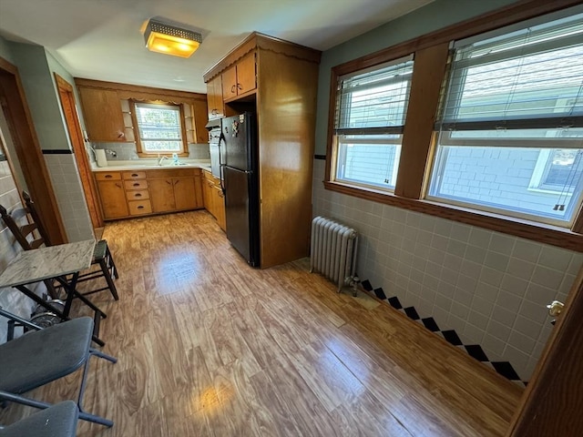 kitchen featuring plenty of natural light, freestanding refrigerator, light wood-style flooring, and radiator heating unit