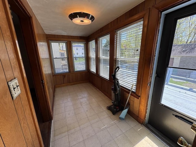 unfurnished sunroom featuring wooden walls and tile patterned flooring
