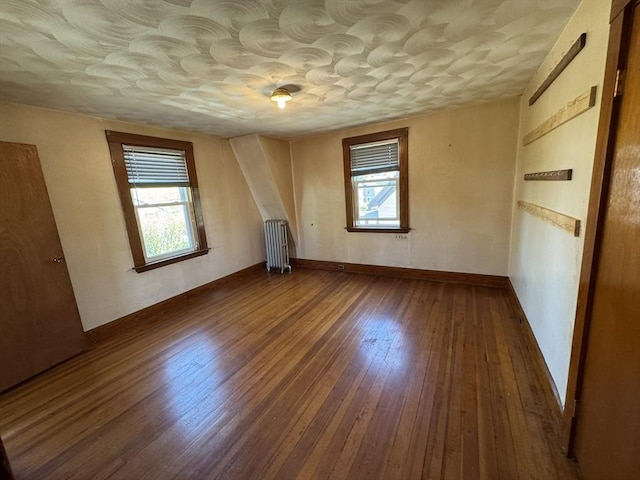 unfurnished bedroom featuring radiator and hardwood / wood-style floors