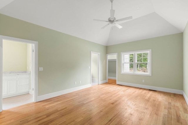 unfurnished bedroom featuring ceiling fan, light wood-type flooring, ensuite bathroom, and vaulted ceiling