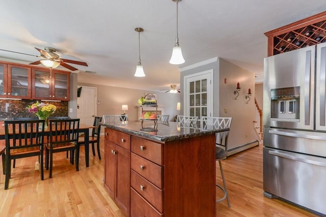 kitchen with pendant lighting, dark stone countertops, a kitchen bar, light hardwood / wood-style floors, and stainless steel fridge with ice dispenser