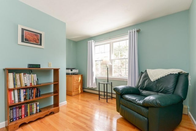 living area with baseboard heating and light hardwood / wood-style floors