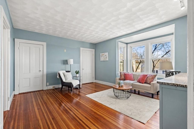 living area featuring wood finished floors, baseboards, and a textured ceiling