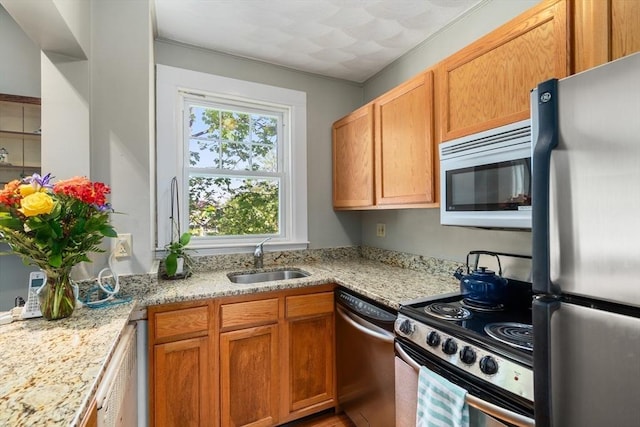 kitchen with light stone counters, appliances with stainless steel finishes, and a sink