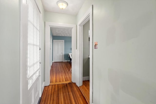 hallway featuring baseboards and wood finished floors