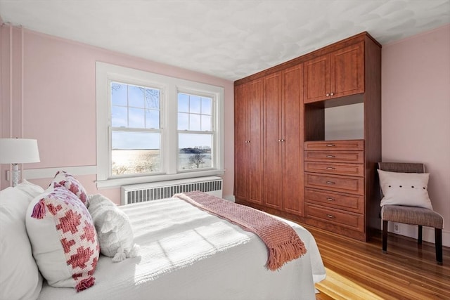 bedroom featuring radiator and wood finished floors