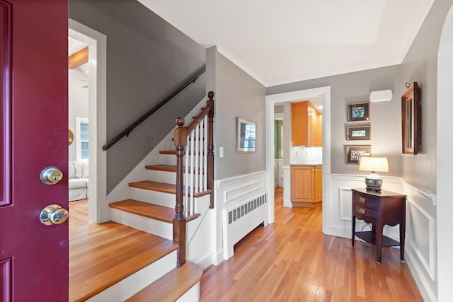 3 Marshall St, North Reading, MA 01864 - entryway with radiator, light wood-type flooring, crown molding, stairs, and a wainscoted wall