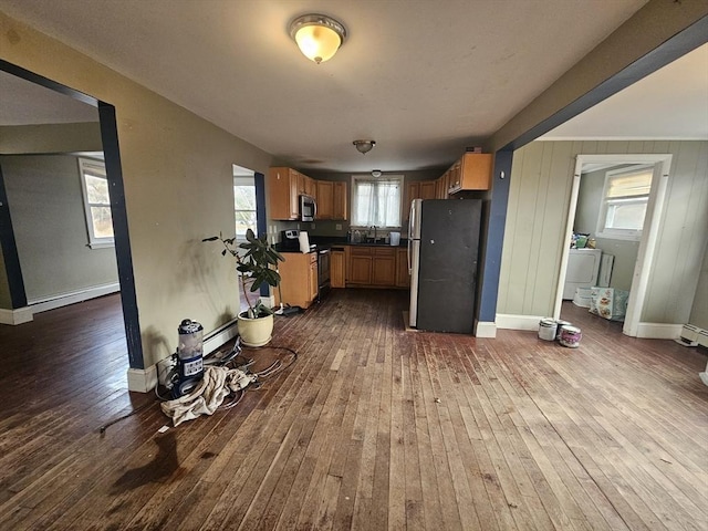 kitchen featuring a baseboard heating unit, washer / clothes dryer, wood-type flooring, sink, and stainless steel appliances