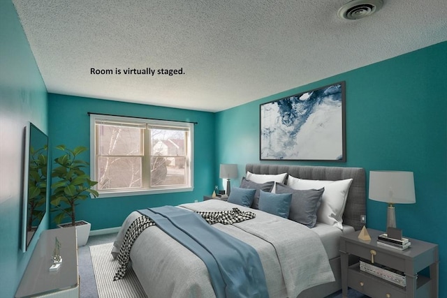 carpeted bedroom featuring visible vents, a textured ceiling, and baseboards