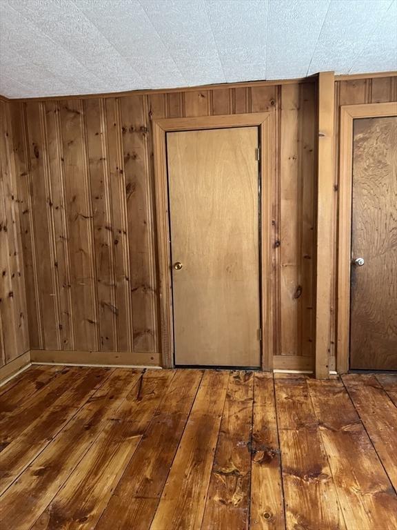 interior space with baseboards, hardwood / wood-style flooring, and wooden walls