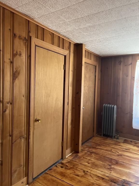 interior space with wooden walls, hardwood / wood-style flooring, and radiator