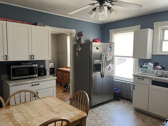 kitchen with light countertops, radiator heating unit, appliances with stainless steel finishes, a ceiling fan, and white cabinetry