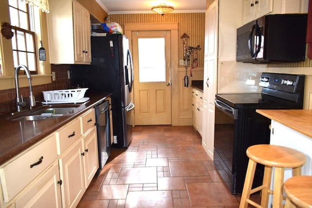 kitchen with sink, crown molding, backsplash, black appliances, and white cabinets