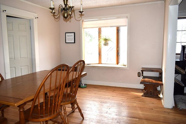 dining space featuring crown molding, a wealth of natural light, light hardwood / wood-style floors, and a chandelier