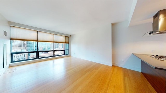 unfurnished living room with wood-type flooring and a wall of windows