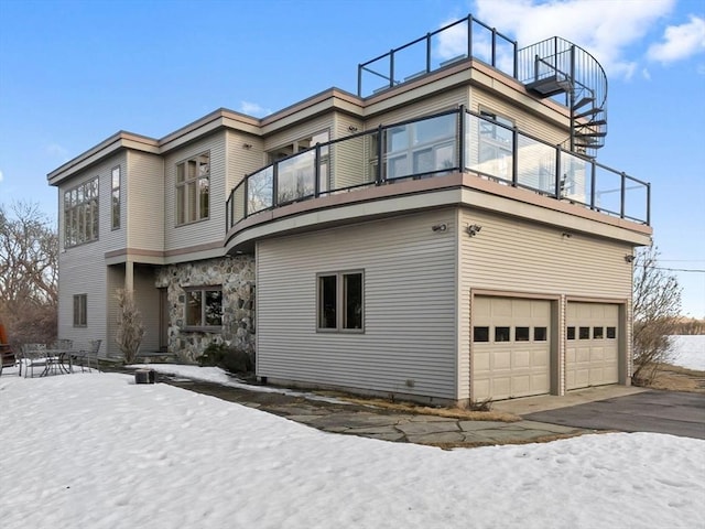 exterior space with stone siding, an attached garage, and a balcony