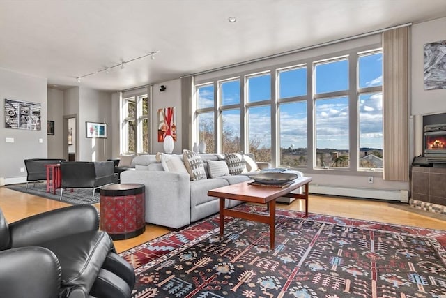 living area featuring a baseboard heating unit, rail lighting, and light wood finished floors