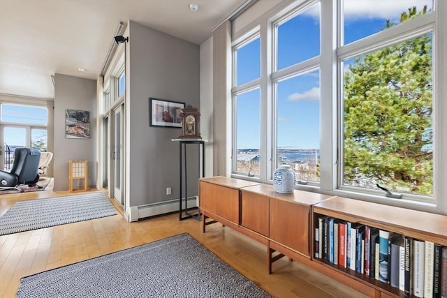 living area with a baseboard heating unit and light wood-type flooring