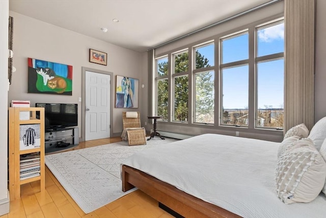 bedroom with light wood-style flooring and baseboard heating