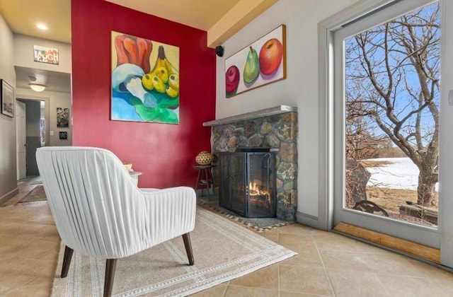 sitting room featuring a stone fireplace and tile patterned floors