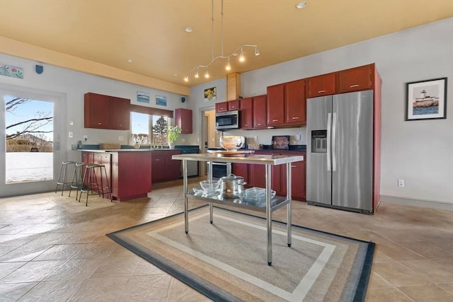 kitchen with reddish brown cabinets, dark countertops, a towering ceiling, appliances with stainless steel finishes, and light tile patterned flooring