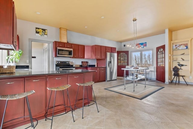 kitchen featuring stainless steel appliances, a peninsula, dark brown cabinets, dark countertops, and pendant lighting