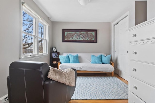 sitting room with a baseboard heating unit and wood finished floors