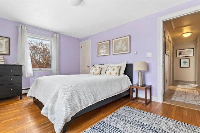 bedroom with baseboards, baseboard heating, and hardwood / wood-style floors