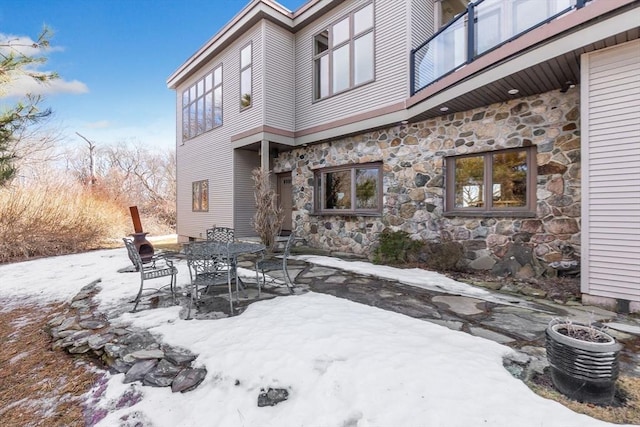 snow covered patio featuring outdoor dining area and a balcony