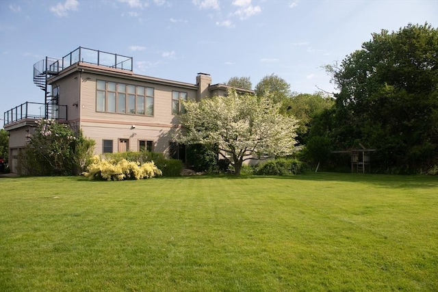 rear view of house featuring a chimney and a lawn