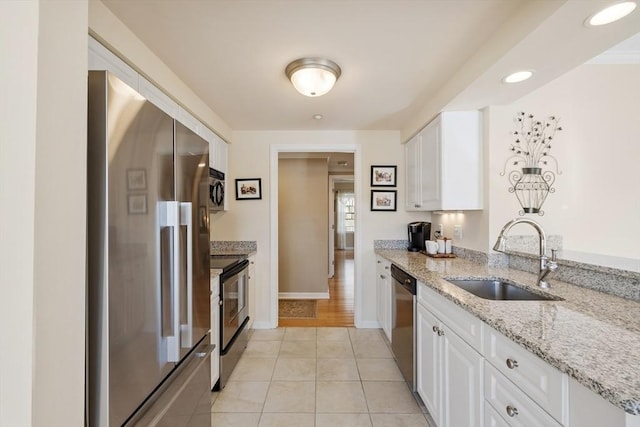 kitchen with appliances with stainless steel finishes, sink, white cabinets, and light stone counters