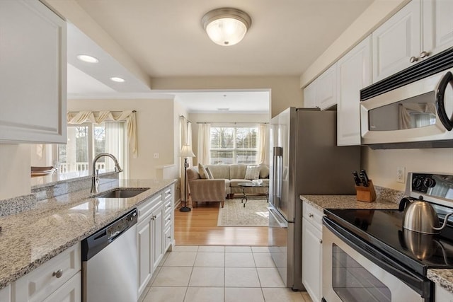 kitchen with white cabinetry, appliances with stainless steel finishes, light stone countertops, and plenty of natural light