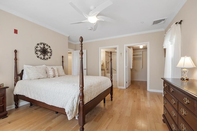 bedroom with ensuite bathroom, a walk in closet, light hardwood / wood-style flooring, ornamental molding, and ceiling fan