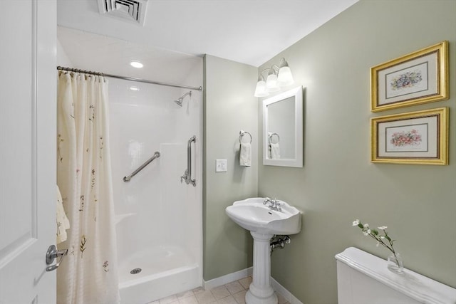 bathroom featuring toilet, curtained shower, and tile patterned flooring