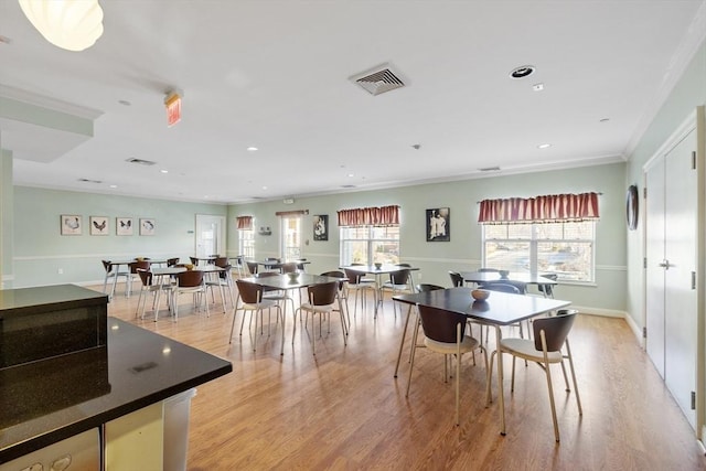 dining room with ornamental molding and light hardwood / wood-style floors