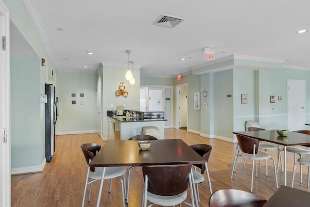 dining room featuring sink, crown molding, and light hardwood / wood-style floors