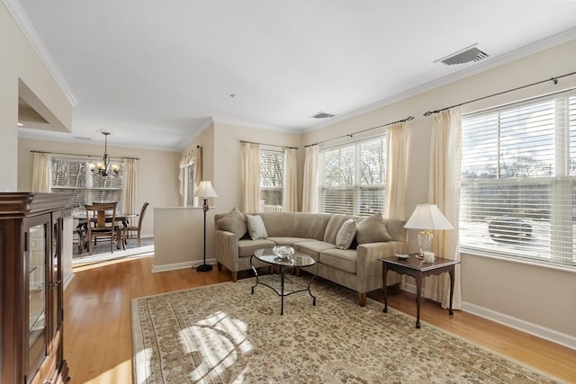 living room with ornamental molding, wood-type flooring, and a chandelier