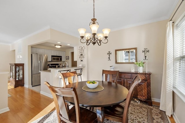 dining area with crown molding, light hardwood / wood-style floors, and a chandelier