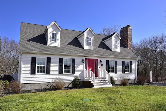 new england style home with a chimney, a front yard, and a shingled roof