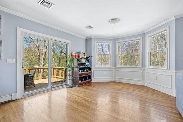 spare room featuring a healthy amount of sunlight, crown molding, and visible vents